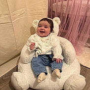 Lyana a rejoint le concours — aidez-le/la à gagner de superbes lots ! baby, child, smiling, happy, indoor, teddy_bear_chair, white_clothing, jeans, socks, soft_toys, curtains, pink, flooring, home_interior, cute, portrait, seated, infant, cozy, furniture