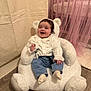 baby, child, smiling, happy, indoor, teddy_bear_chair, white_clothing, jeans, socks, soft_toys, curtains, pink, flooring, home_interior, cute, portrait, seated, infant, cozy, furniture