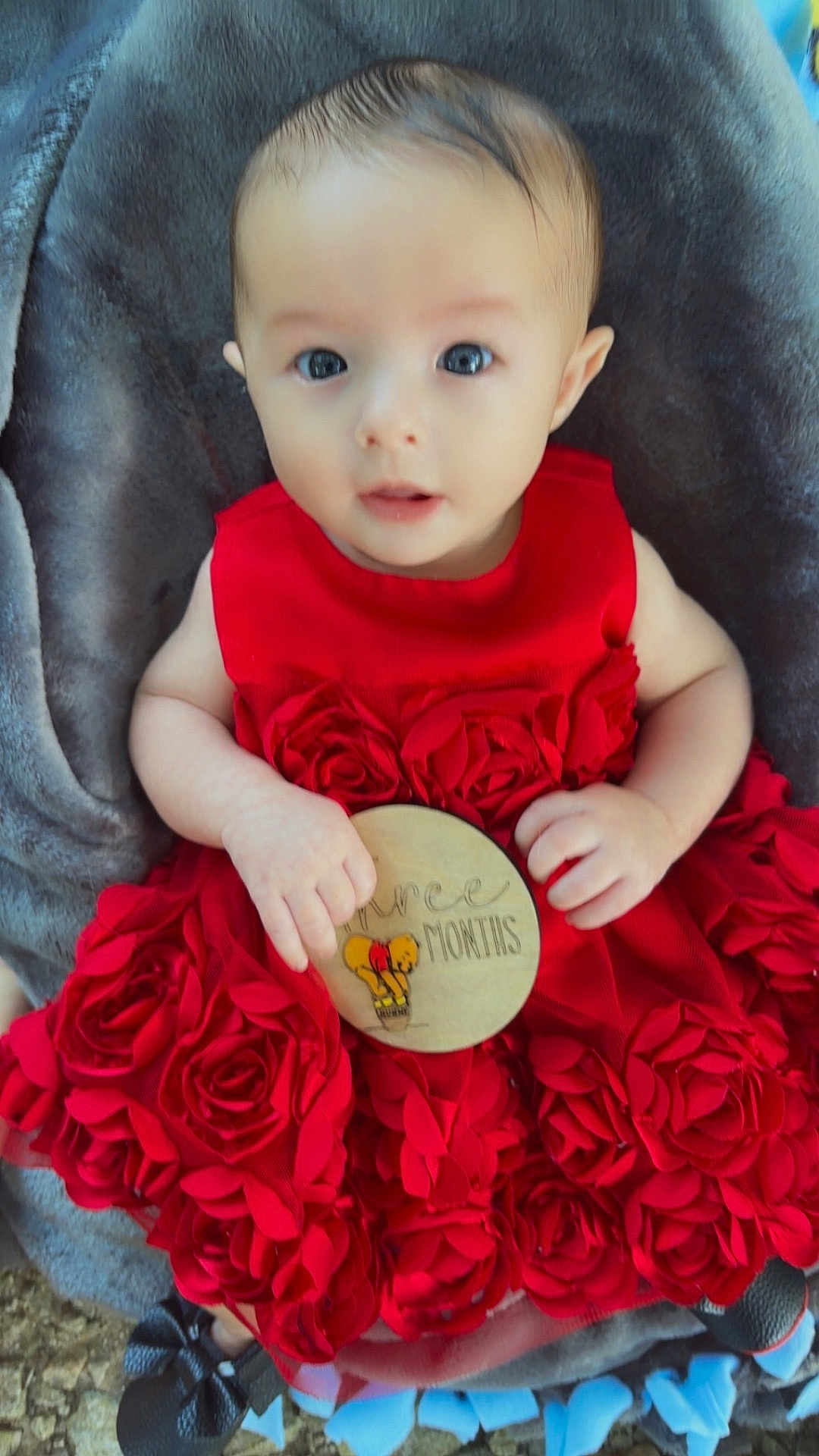 Sirena is registered to the contest to win money with this photo: baby, child, red_dress, fabric_roses, plaque, winnie_the_pooh, three_months, blanket, soft_texture, cute, wide_eyes, infant, holding, sitting, indoors, portrait, adorable, clothing, person, closeup