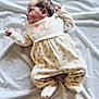 baby, blanket, child, clothing, cozy, curly_hair, cute, floral, footed_pajamas, indoors, infant, lying_down, newborn, onesie, portrait, resting, side_view, small_hands, soft, warm