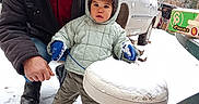 Léo participe au concours pour gagner de l'argent avec cette photo : adult, car, child, clothing, cold, footwear, grass, hood, jacket, man, mittens, nature, outdoor, people, portrait, snow, stool, toddler, trees, winter