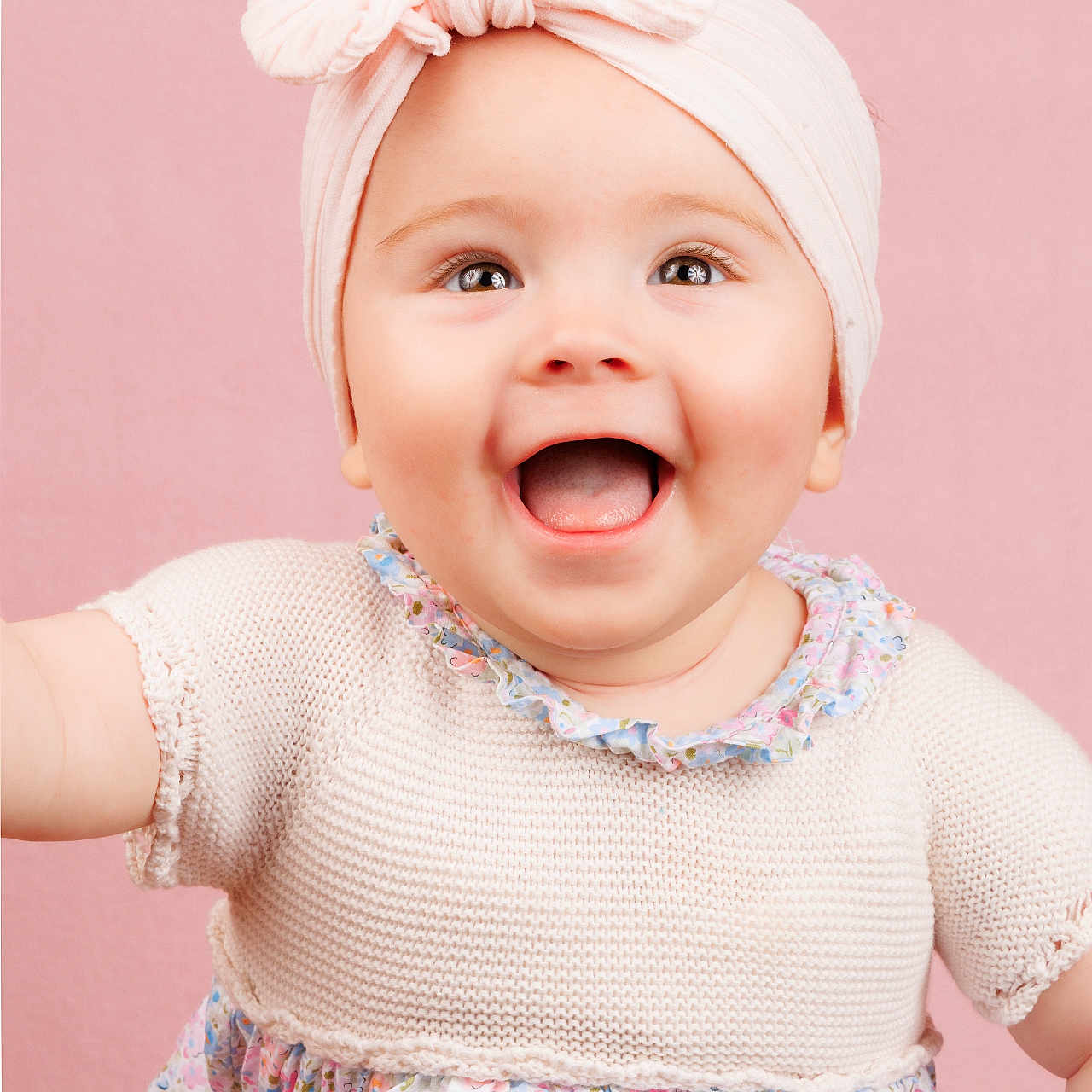 Eden a rejoint le concours — aidez-le/la à gagner de superbes lots ! baby, background, bow, child, clothing, cute, dress, face, floral, hand, happy, headband, infant, person, pink, portrait, reaching, skin, smiling, studio