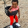 Zara joined the competition — help win amazing prizes! toddler, child, swing, playground, red_pants, white_sneakers, smiling, happy, outdoor, bucket_swing, wood_chips, chain_link_fence, curly_hair, casual_clothing, fun, play, person, daytime, active, joy