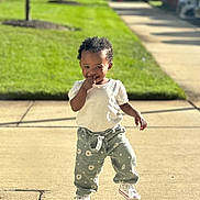Zara is registered to the contest to win money with this photo: toddler, child, smiling, sidewalk, sunlight, green_lawn, pants, sneakers, short_sleeve_shirt, outdoor, daytime, curly_hair, walking, cute, playful, suburban, shadow, happy, person, casual_clothing