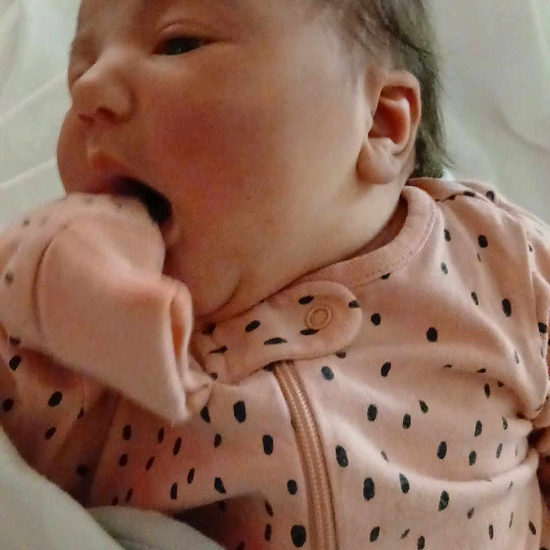 Gina joined the competition — help win amazing prizes! baby, infant, newborn, onesie, pink_clothing, polka_dots, blanket, sleepwear, face, hand, cute, child, portrait, indoor, resting, young, small, human, person, cozy