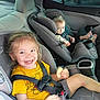 Ezekiel is registered to the contest to win money with this photo: child, car_seat, smiling, snack, happy, car_interior, seatbelt, toddler, baby, yellow_shirt, shorts, footwear, window, seat, hair, face, person, safety, travel, cute