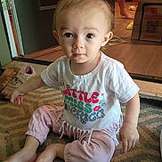 Ensley is registered to the contest to win money with this photo: bag, barefoot, casual, child, curious, cute, door, expression, floor, home, indoor, person, pigtails, pink_pants, rug, shirt, shoes, sitting, toddler, young_child