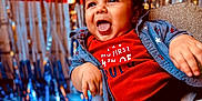 Abran is registered to the contest to win money with this photo: baby, child, high_chair, red_shirt, celebration, 4th_of_july, smiling, happy, curly_hair, festive, party, colorful_background, indoor, clothing, seat_belt, portrait, infant, fun, holiday, person