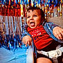 baby, child, high_chair, red_shirt, celebration, 4th_of_july, smiling, happy, curly_hair, festive, party, colorful_background, indoor, clothing, seat_belt, portrait, infant, fun, holiday, person