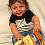 baby, child, smiling, toy, plush_toy, striped_background, jeans, black_shirt, white_shirt, barefoot, happy, cute, indoor, portrait, human, infant, sitting, hand, feet, face