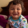 baby, child, smiling, happy, wet_hair, onesie, cartoon_print, sitting, indoors, closeup, face, cute, joyful, skin, person, soft_surface, background_blur, expression, infant, portrait