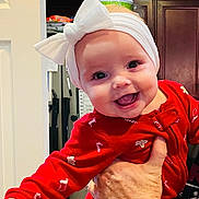 Adeline joined the competition — help win amazing prizes! baby, infant, smiling, red_clothing, white_bow, headband, hand, kitchen, cabinet, door, holiday_theme, candy_cane_pattern, gingerbread_pattern, indoor, person, happy, closeup, cute, cheerful, child