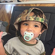 Miriam joined the competition — help win amazing prizes! toddler, child, pacifier, hat, camo_hat, shirt, duck, moose, sitting, indoor, couch, cute, baby, young_child, clothing, face, person, smiling, headwear, casual