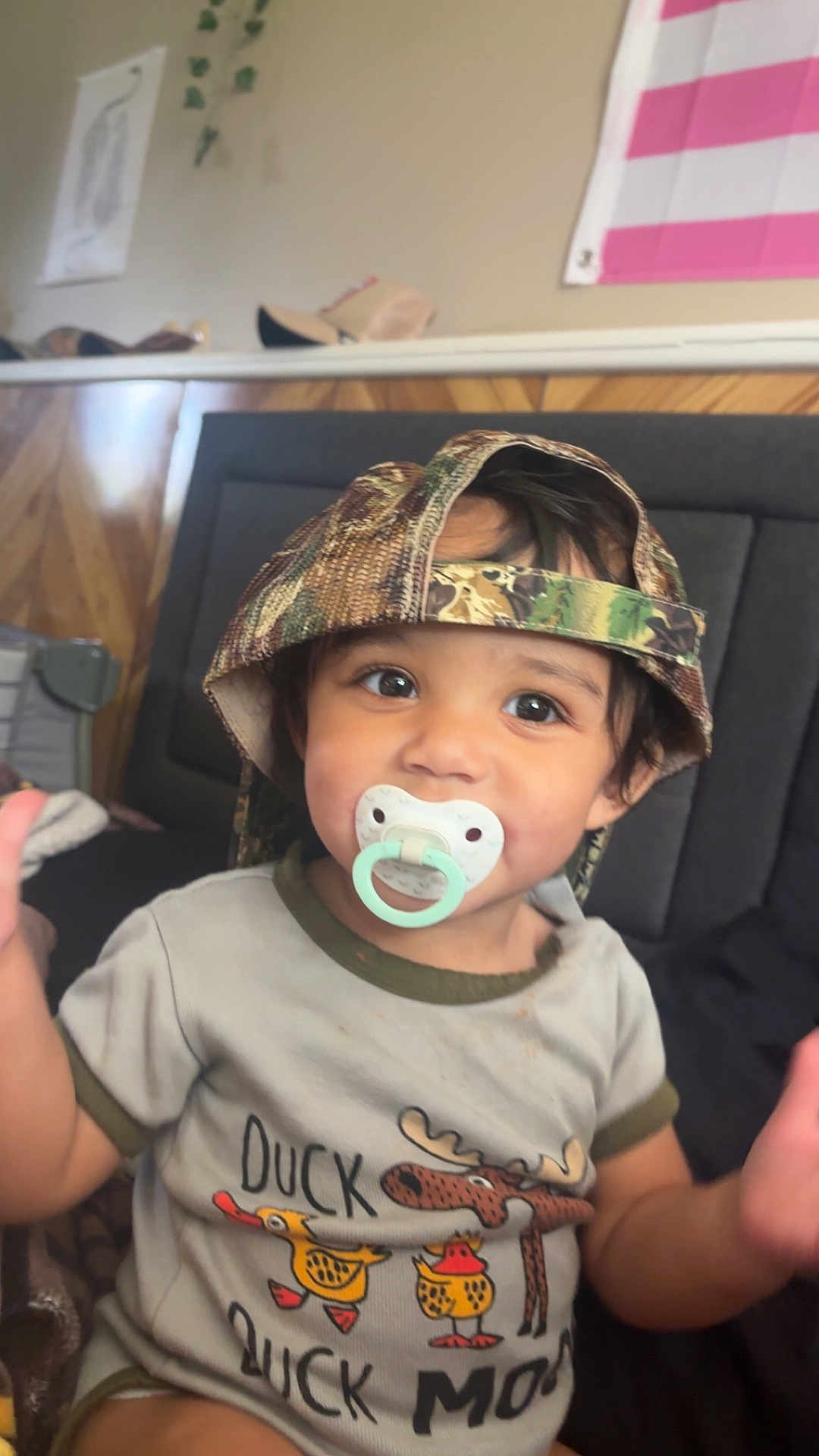 Miriam joined the competition — help win amazing prizes! toddler, child, pacifier, hat, camo_hat, shirt, duck, moose, sitting, indoor, couch, cute, baby, young_child, clothing, face, person, smiling, headwear, casual