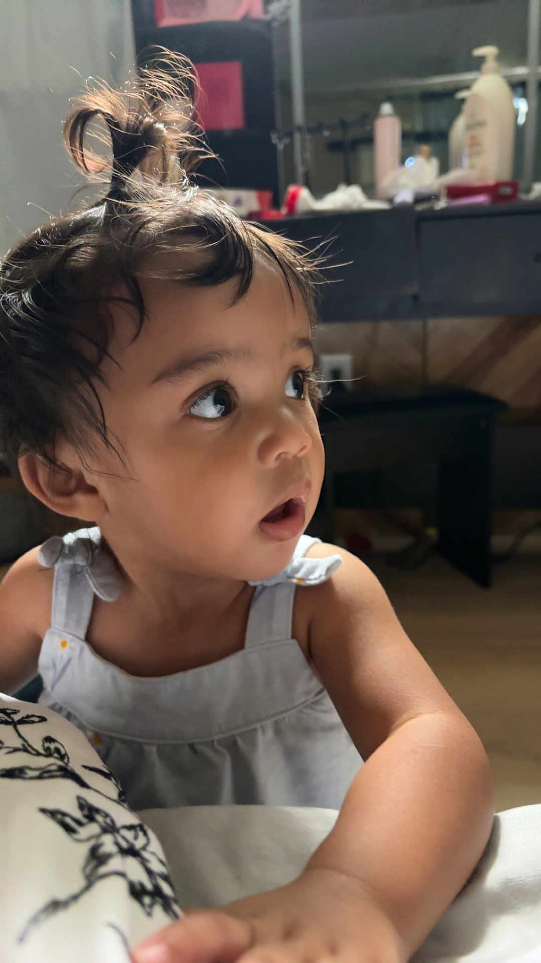 Miriam is registered to the contest to win money with this photo: toddler, child, indoor, portrait, curious, messy_hair, topknot, blue_dress, skin, face, hand, expression, person, baby, young_child, furniture, blurred_background, natural_light, cute, casual