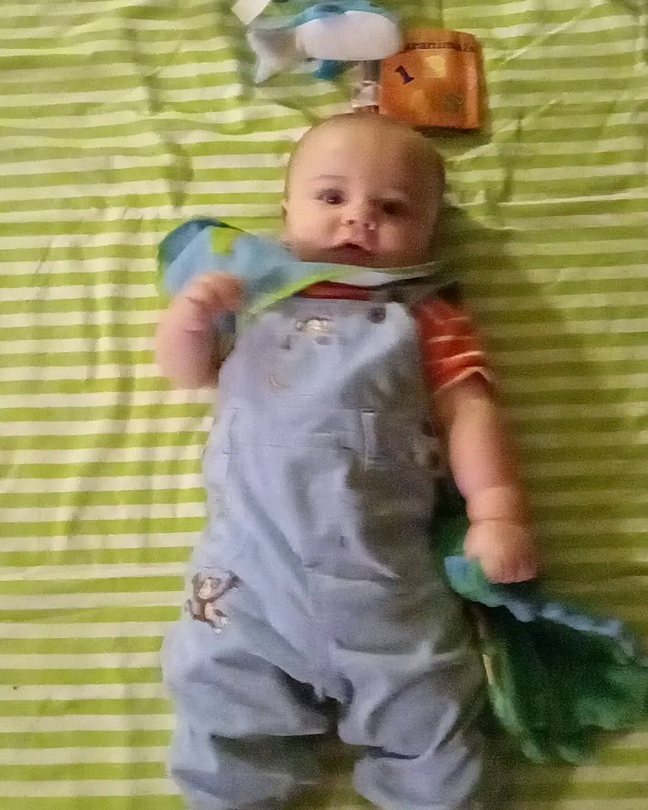 Nathaniel is registered to the contest to win money with this photo: baby, baby_products, baby_safety, baby_toddler_clothing, baby_toys, bedding, cheek, child, comfort, gesture, happy, linens, pattern, person, play, sleeve, smile, thumb, toddler