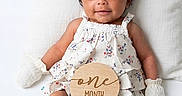 Victoria is registered to the contest to win money with this photo: baby, infant, one_month, smiling, pigtails, bow, mittens, floral_dress, sandals, pillow, toys, starfish, fish_toy, green_toy, white_background, cute, portrait, child, lying_down, happy