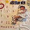 Victoria is registered to the contest to win money with this photo: baby, infant, milestone_blanket, floral_outfit, bonnet, sandals, ultrasound_images, plush_toy, turtle, sunglasses, numbers, months, lying_down, cute, child, indoors, soft_toys, fabric, baby_clothes, portrait
