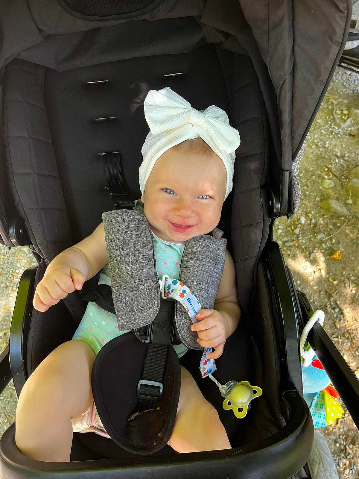 Alice a rejoint le concours — aidez-le/la à gagner de superbes lots ! baby, child, stroller, headband, pacifier, smile, blue_eyes, sunlight, outdoor, infant, clothing, seatbelt, playful, happy, person, cute, toy, nature, seat, portrait