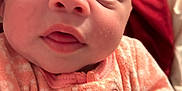 Lilliona is registered to the contest to win money with this photo: baby, infant, face, eyes, expression, pink_clothing, patterned_outfit, closeup, person, skin, head, mouth, newborn, cute, indoors, soft_texture, sleepwear, child, human, apparel
