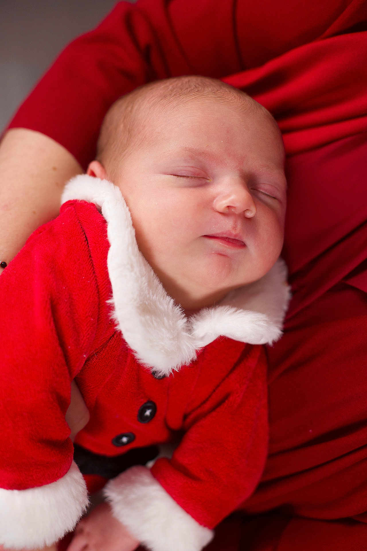 Liziana a rejoint le concours — aidez-le/la à gagner de superbes lots ! baby, sleeping, infant, red_clothing, santa_outfit, white_fur_trim, closeup, portrait, person, child, holiday, christmas, cozy, warm, hands, resting, cute, soft_texture, indoor, festive