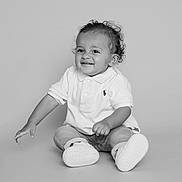 Izaac a rejoint le concours — aidez-le/la à gagner de superbes lots ! child, toddler, smiling, sitting, curly_hair, white_polo, jeans, sneakers, studio, portrait, happy, baby, cute, fashion, clothing, monochrome, black_and_white, person, young, innocent