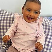 Innayah participe au concours pour gagner de l'argent avec cette photo : baby, child, smile, happy, girl, purple_bow, pink_sweater, hearts_pattern, pants, checkered_pillow, cushion, sitting, indoor, portrait, cute, infant, furniture, face, person, joy