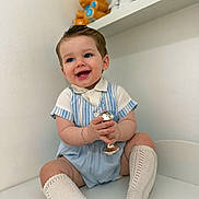 Elijah-James joined the competition — help win amazing prizes! baby, child, smiling, blue_eyes, striped_clothing, knit_socks, rattle, toy, teddy_bear, sitting, indoor, white_wall, shelf, cute, happy, portrait, infant, playful, bracelet, soft_lighting