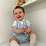 baby, child, smiling, blue_eyes, striped_clothing, knit_socks, rattle, toy, teddy_bear, sitting, indoor, white_wall, shelf, cute, happy, portrait, infant, playful, bracelet, soft_lighting