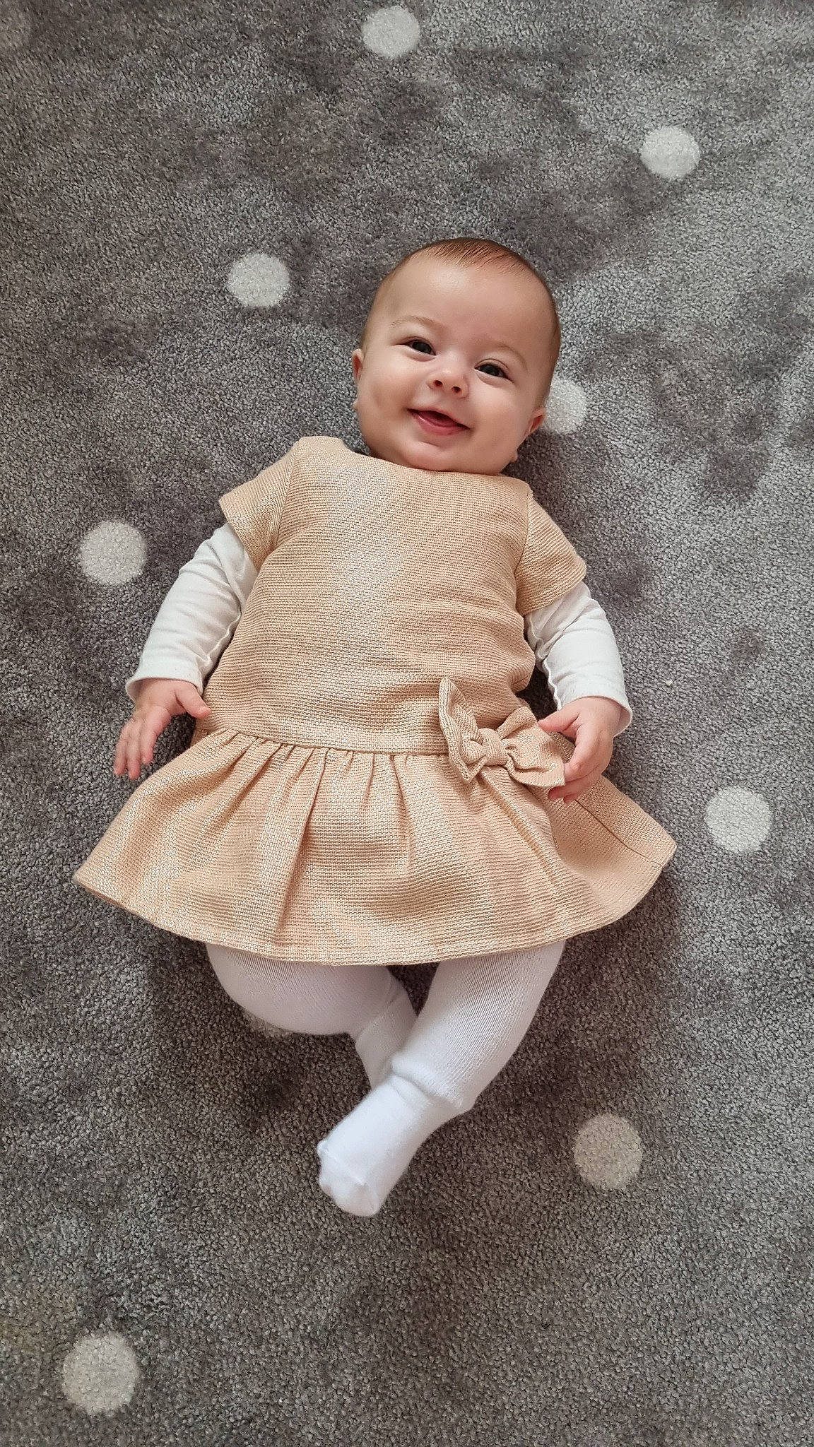 Leyna a rejoint le concours — aidez-le/la à gagner de superbes lots ! baby, baby_toddler_clothing, barefoot, cheek, child, day_dress, face, fashion_accessory, flooring, happy, human_leg, joy, outerwear, pattern, person, ruffle, sitting, skin, sleeve, smile