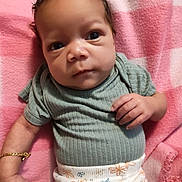 Miracle joined the competition — help win amazing prizes! baby, infant, face, hand, bracelet, clothing, green_shirt, patterned_pants, pink_blanket, close_up, portrait, person, skin, expression, alert, lying_down, indoors, soft_lighting, watermark, text_overlay