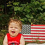 Rory joined the competition — help win amazing prizes! baby, child, smiling, outdoor, grass, blanket, american_flag, greenery, tank_top, happy, cute, infant, nature, summer, portrait, sitting, red_clothing, grass_field, face, person