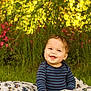 baby, child, smiling, grass, blanket, outdoor, nature, flowers, greenery, happy, portrait, toddler, striped_shirt, sunlight, cute, sitting, face, cheerful, playful, young