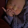 newborn, baby, sleeping, hoodie, purple_clothing, floral_pattern, hand, face, cozy, infant, child, soft_light, portrait, closeup, peaceful, cute, zipped_clothing, person, indoors, resting