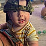 Theo joined the competition — help win amazing prizes! baby, blanket, camo, carpet, casual_clothing, child, couch, curious, expression, face, furniture, hat, home, indoor, infant, person, reaching, striped_shirt, toy, young_child