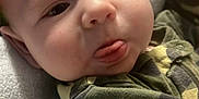 Theo joined the competition — help win amazing prizes! baby, blanket, camo, child, closeup, clothing, cozy, cute, expression, face, hand, indoor, infant, person, portrait, resting, skin, soft, tongue, young