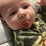 baby, blanket, camo, child, closeup, clothing, cozy, cute, expression, face, hand, indoor, infant, person, portrait, resting, skin, soft, tongue, young