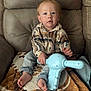 Theo joined the competition — help win amazing prizes! armchair, barefoot, blanket, blue_toy, casual_clothing, child, curious, face, furniture, home, indoor, jeans, light_skin, patterned_blanket, person, plaid_shirt, seated, short_hair, toddler, toy