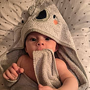 Leo participe au concours pour gagner de l'argent avec cette photo : baby, towel, hooded_towel, infant, face, hand, blanket, pattern, triangle_pattern, skin, cute, soft_texture, wrapped, bed, sleepwear, child, newborn, portrait, indoors, comfort