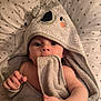 baby, towel, hooded_towel, infant, face, hand, blanket, pattern, triangle_pattern, skin, cute, soft_texture, wrapped, bed, sleepwear, child, newborn, portrait, indoors, comfort