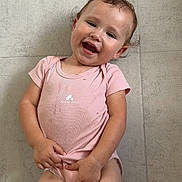 Mïa participe au concours pour gagner de l'argent avec cette photo : toddler, child, smiling, pink_onesie, floor, tile, barefoot, toy, cloth, happy, baby, skin, person, cute, indoor, casual, lying_down, playful, young_child, expression