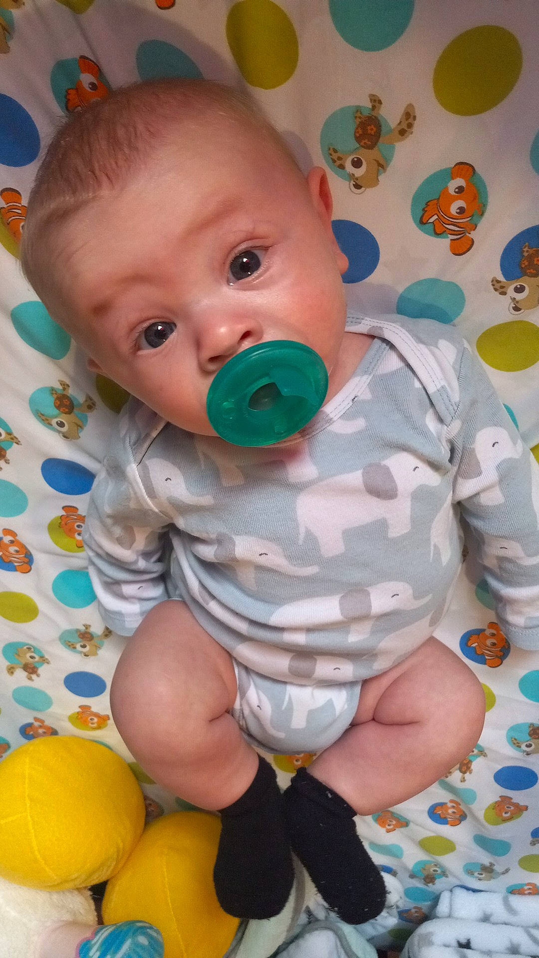 Kyler is registered to the contest to win money with this photo: baby, baby_playing_with_toys, baby_products, baby_toddler_clothing, baby_toys, cheek, child, face, facial_expression, fun, happy, linens, pattern, person, room, sitting, skin, textile, toddler, white