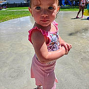 Aliya is registered to the contest to win money with this photo: child, toddler, swimsuit, pink, water, wet, outdoor, playground, park, summer, sunlight, grass, slide, splash_pad, sandals, people, fun, daytime, cute, portrait