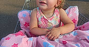 Aliya is registered to the contest to win money with this photo: toddler, child, shopping_cart, blanket, pink, stars, parking_lot, hand, sandals, outdoor, sunlight, curly_hair, clothing, person, cute, expression, comfort, sitting, daytime, retail