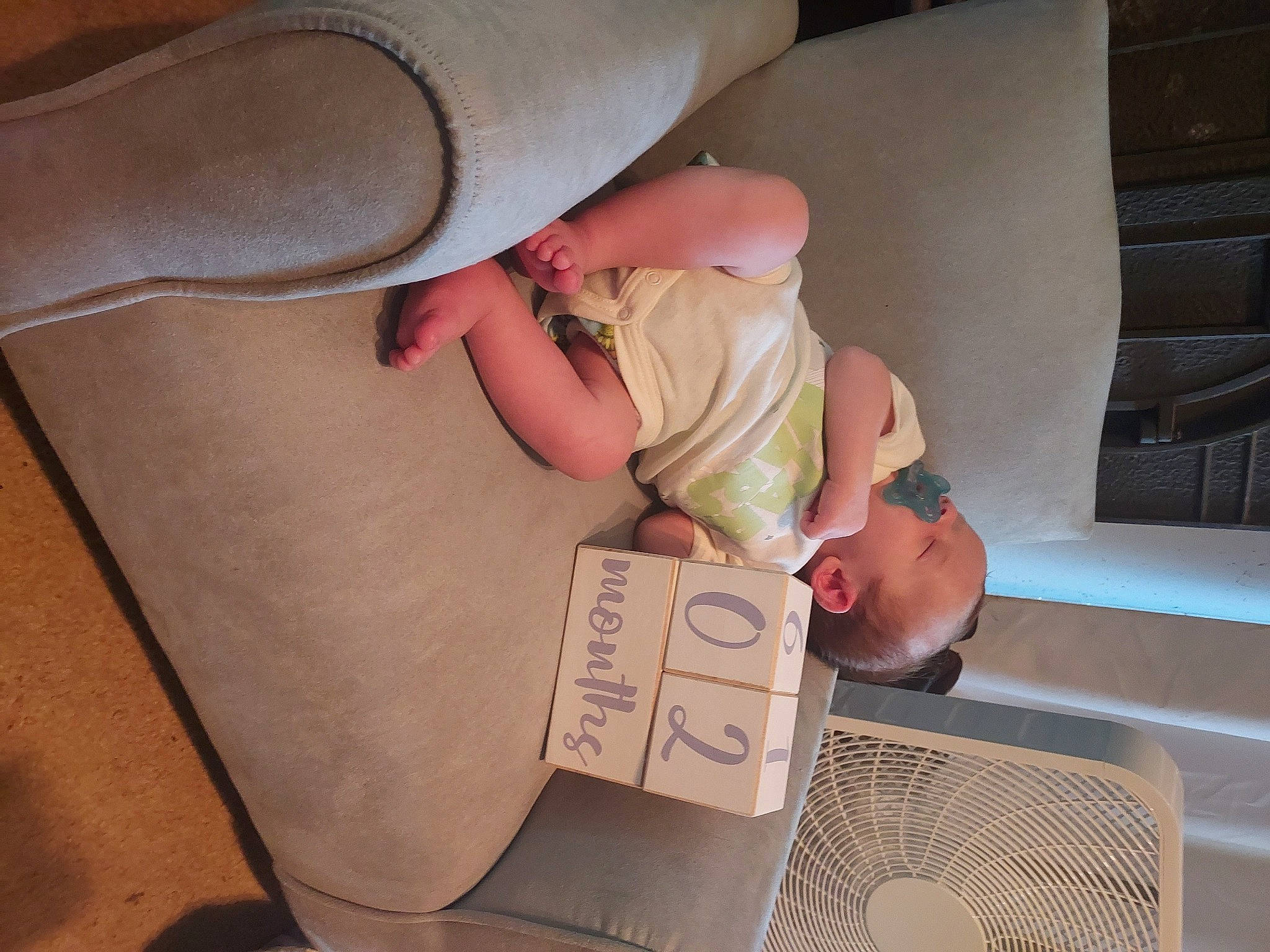 Apollo is registered to the contest to win money with this photo: baby, baby_products, baby_toddler_clothing, child, comfort, couch, finger, flooring, human_leg, knee, lap, leg, linens, person, shipping_box, shoulder, sitting, sock, thigh, toddler