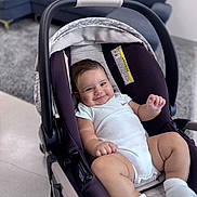 Miguel is registered to the contest to win money with this photo: baby, infant, child, smiling, portrait, car_seat, indoors, living_room, sofa, rug, home, onesie, socks, seated, reclining, happy, face, short_hair, furniture, photography