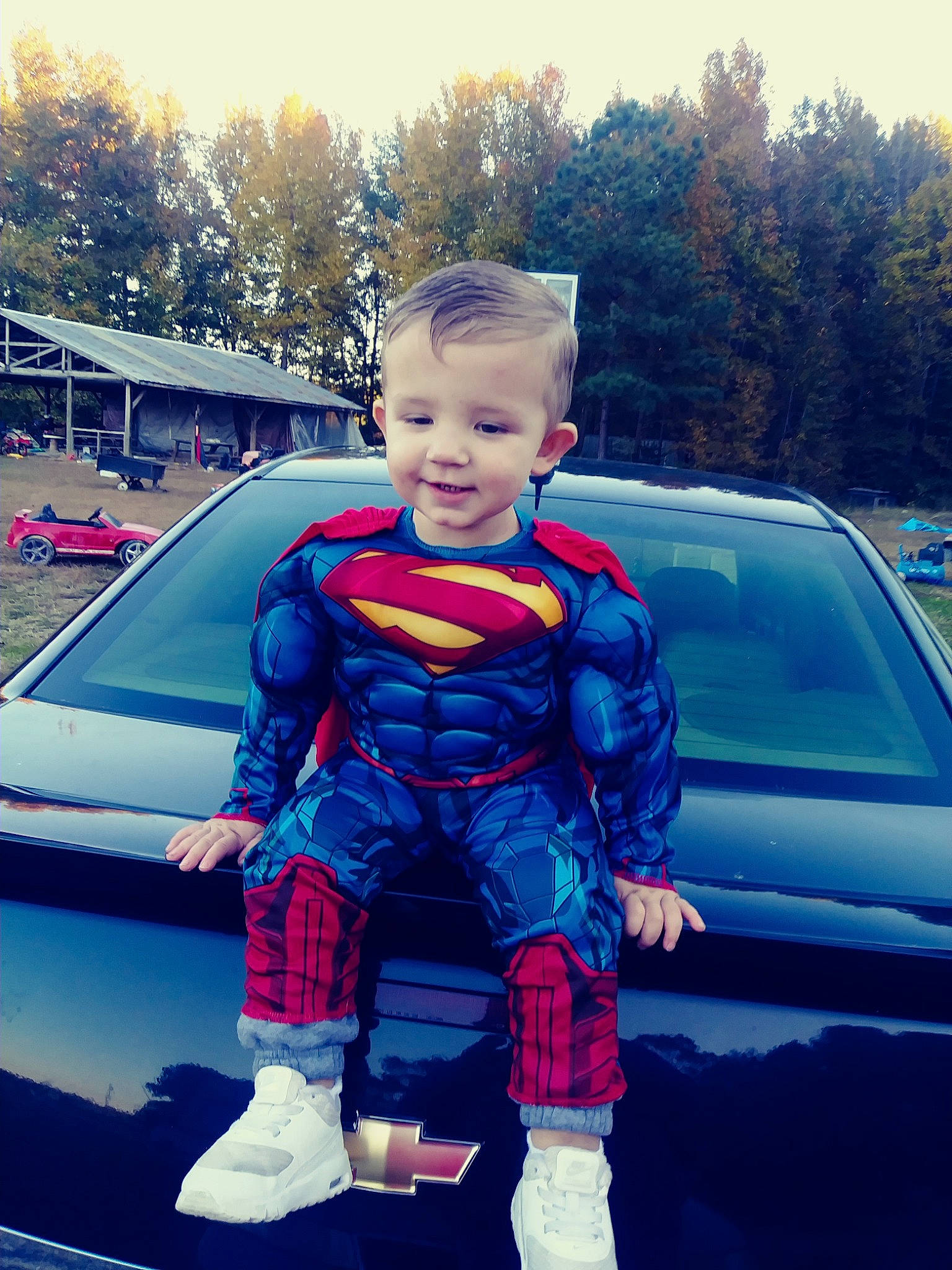 Logan is registered to the contest to win money with this photo: blue, car, child, cool, face, fictional_character, hairstyle, head, joy, justice_league, male, person, red, sky, spider_man, standing, superhero, superman, textile, toddler