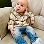 armchair, baby, blue_jeans, casual_clothing, child, curious, cute, expression, face, furniture, head, indoor, infant, legs, person, plaid_shirt, seated, small_hands, socks, surprised