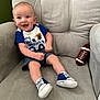 Randy is registered to the contest to win money with this photo: baby, child, smiling, sitting, armchair, plush, clothing, shorts, sneakers, toy, football, happy, cute, indoor, person, face, head, blue, gray, casual