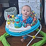 baby, child, walker, pajamas, toys, floor, wooden_floor, cabinet, trash_can, indoor, curious, colorful, playtime, foot, face, person, home, furniture, expression, early_childhood